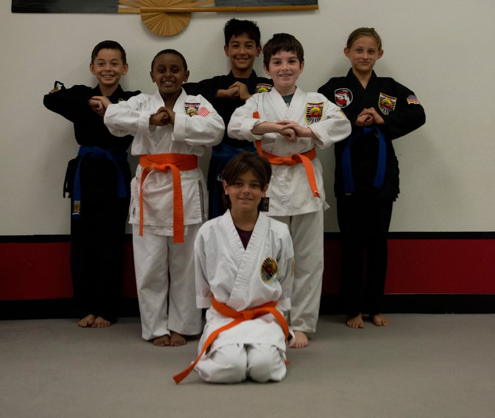 Six young karate students in white and black gis standing together in a salute at USSD Santa Barbara.